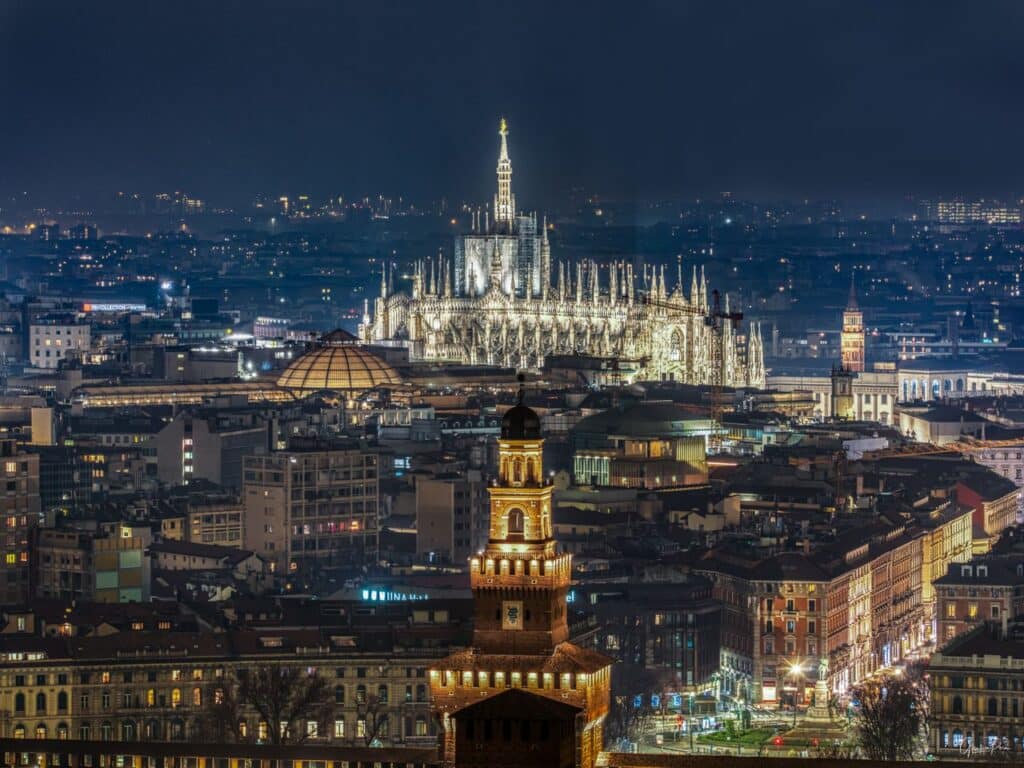 Stunning aerial night view of Milan featuring the illuminated Duomo Cathedral and cityscape.